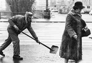 Sidewalks: Man sprinkles salt on a sidewalk 1983
