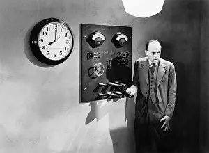 Midadult: Man standing next to an electrical switch