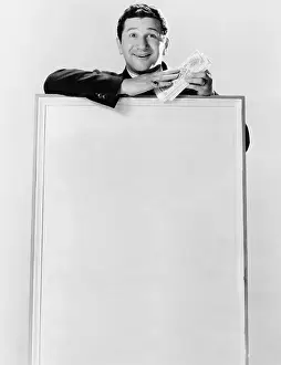 Miserly: Man standing behind an information board and holding