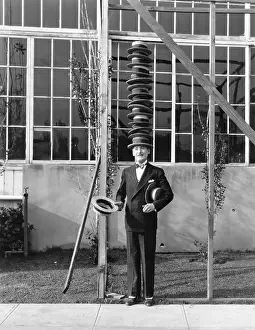 Skillfulness: Man standing with stack of hats on head
