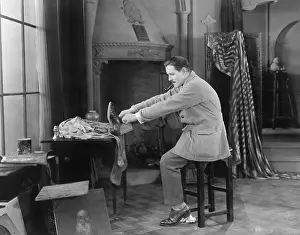 Thirtysomething: Man in his studio putting on shoes