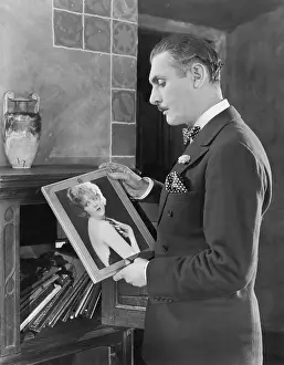 Woeful: Man studying a picture of a woman