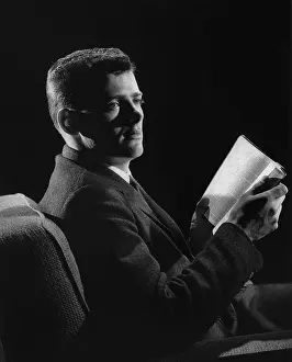 Camerique: Man in suit sitting in dim light reading a book
