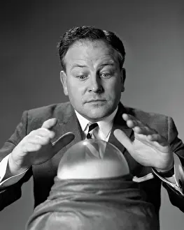 Clairvoyant: Man in suit & tie looking down at crystal ball