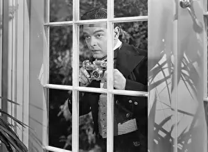 Peeking: Man taking pictures through window
