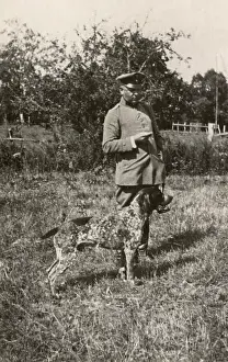Spotty: Man in uniform with a dog in a field, Germany