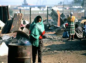 Squatter: A man, wrapped in a blanket, warms himself next