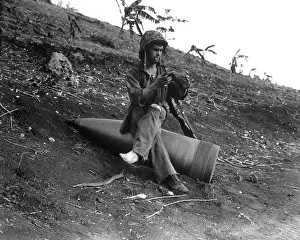 Forager: A Marine sits on an 16-inch naval shell to shake