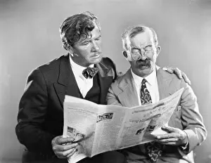 Mustaches: Two mature men reading a newspaper together