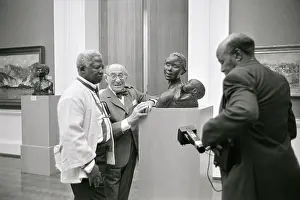 Stature: Three men in an art gallery stand around the statue