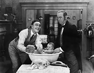 Chuckling: Two men giving a baby a bath