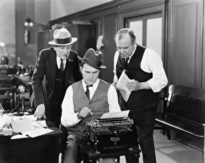 Employ: Three men in an office hunched over a typewriter