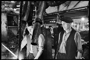 Millfield: Two men operating glass blowing machinery at the