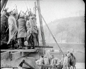 Raises: Men Operating A Manual Pile Driver. They Are