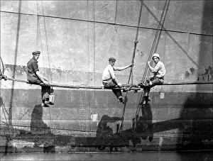 Planks: Men painting the side of a large boat