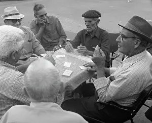 Trilby: Six men playing cards at a table in the street