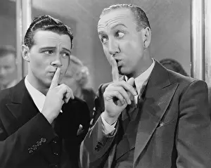 Exaggerated: Two men saying be quiet with finger to lips