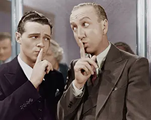 Exaggerated: Two men saying be quiet with finger to lips