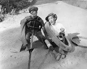 Surplus: Two men sitting on a ground pretending to drive