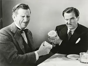 Squeezing: Two men squirting grapefruit juice at each other -