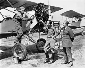 Employ: Three men standing next to an aircraft having a