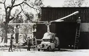 Unusual Design: Men Standing on Ladders Attaching the Rotors Onto a Heli?