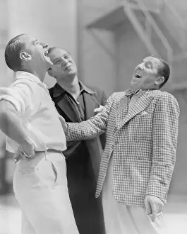 Chuckling: Three men standing together and laughing