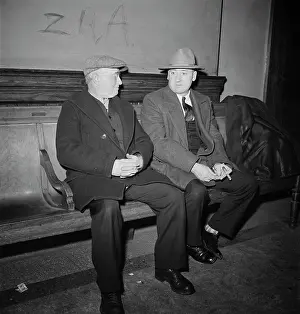 Clasped: Men talking on bench while waiting for next