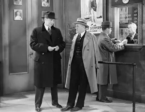 Fedoras: Men talking in theater lobby