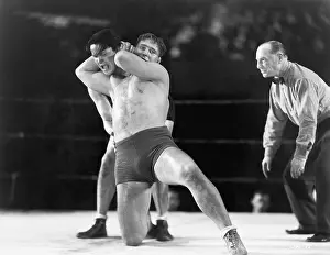 Workouts: Two men wrestling with referee making a call in