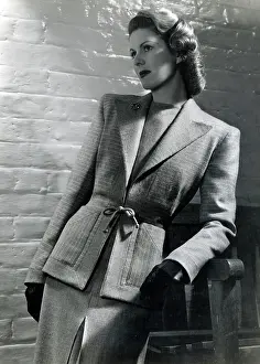 Belted: Model leaning against a bench, smart two-piece wool suit