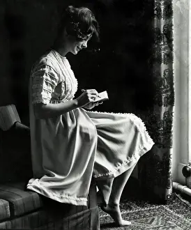 Nightgown: Model in a multi-part nightgown sits on sofa arm with diary