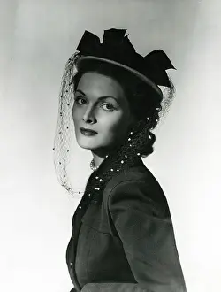 Sideways: Model wearing a sophisticated small round hat with veil