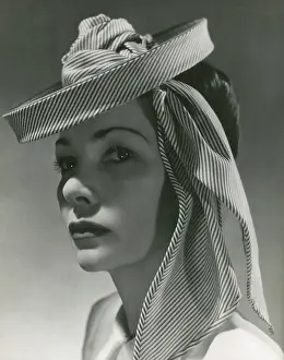 Millinery: Model wearing a thin stripe circular hat or fascinator