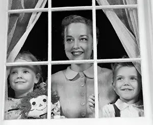 Raggedy: Mom with two kids looking out window towards