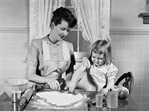 Cooperate: Mother & daughter baking together in kitchen