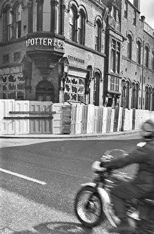 Boarded: Motorcyclist approaching boarded up buildings