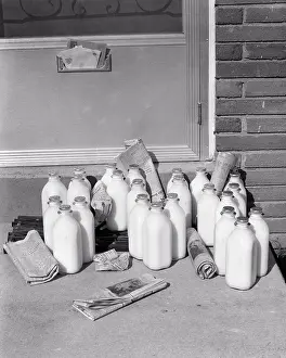 Stoop: Multiple Glass Bottles of Milk and Newspapers
