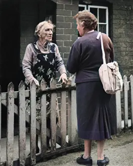 Neighbours: Two neighbours chatting over a fence