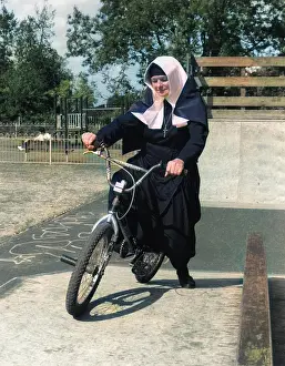 Nuns: Nun on a bicycle in a playground