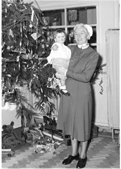 Herts: Nurse holding child next to Christmas tree