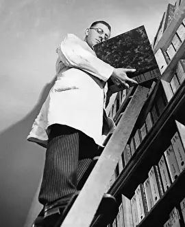 Arranges: Office worker organizing filing shelves, 1935
