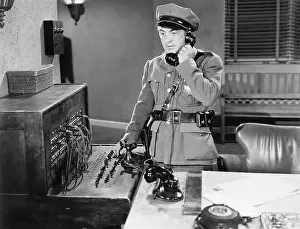 Bureaus: Officer talking on a telephone next to a switchboard