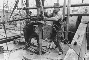 Wrenches: Oil field workers adding a length of pipe to drill stream by