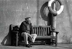 Lifebelt: An old man on a bench in the harbour at Ramsey, Isle of Man