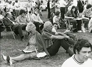 Shirley Baker: Older couple sitting back-t-back at an outdoor show