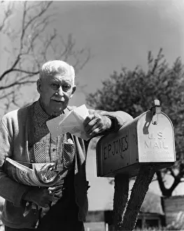Pausing: Older Gentleman Leaning On His Mailbox Gathering His Mail