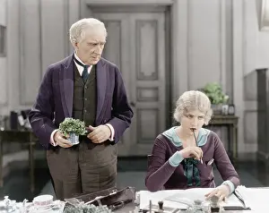 Saddened: Older man standing next to a woman at her desk