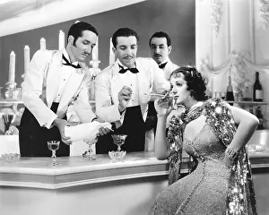Pamper: Two overly attentive waiters light a woman's cigarette