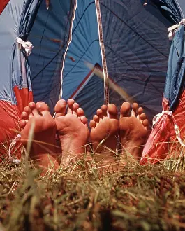Shoeless: Two Pair Bare Feet Sticking Out Tent Grass